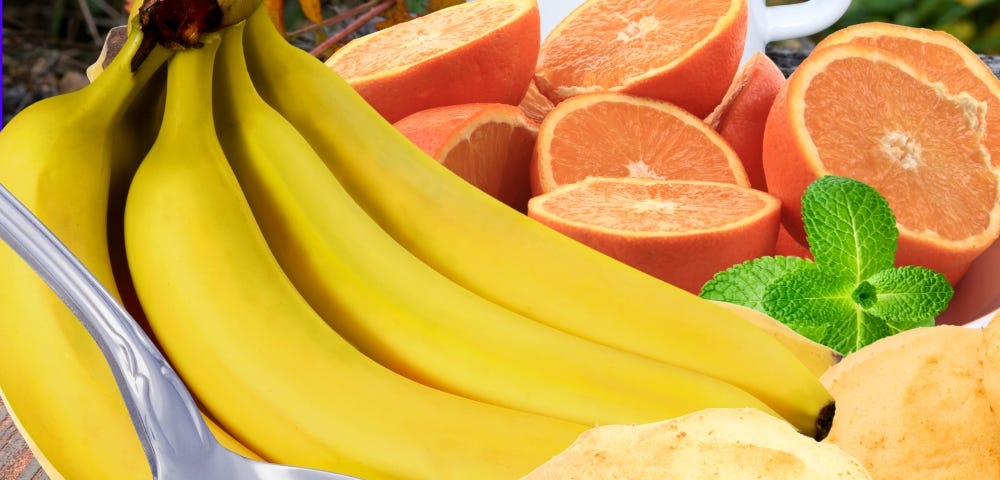 Yellow bananas, bright oranges, cookies in a spoon and a hot cup of tea.