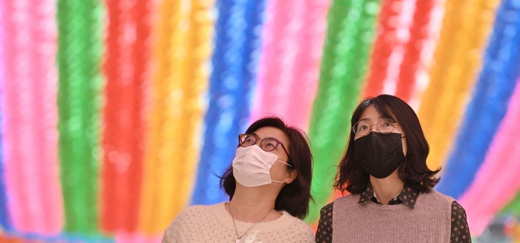 A photo of two Korean women wearing face masks at Jogyesa Temple in South Korea.