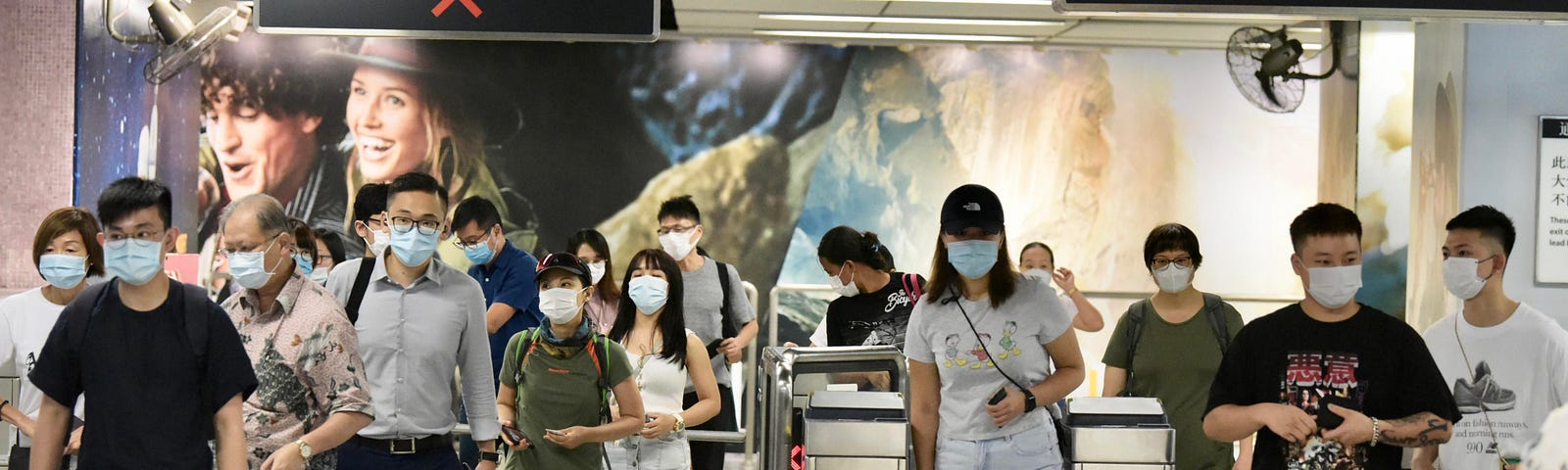 People wearing masks go through ticket barrier at the railway station in Hong Kong.