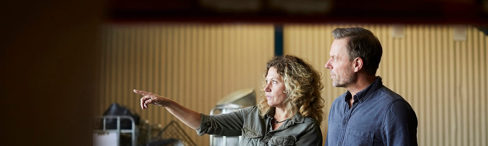 A photo of two colleagues in a warehouse, one of them is pointing to the left.