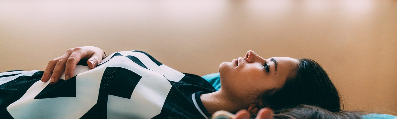 A young woman lies down and stares at the ceiling, holding her phone and feeling worried