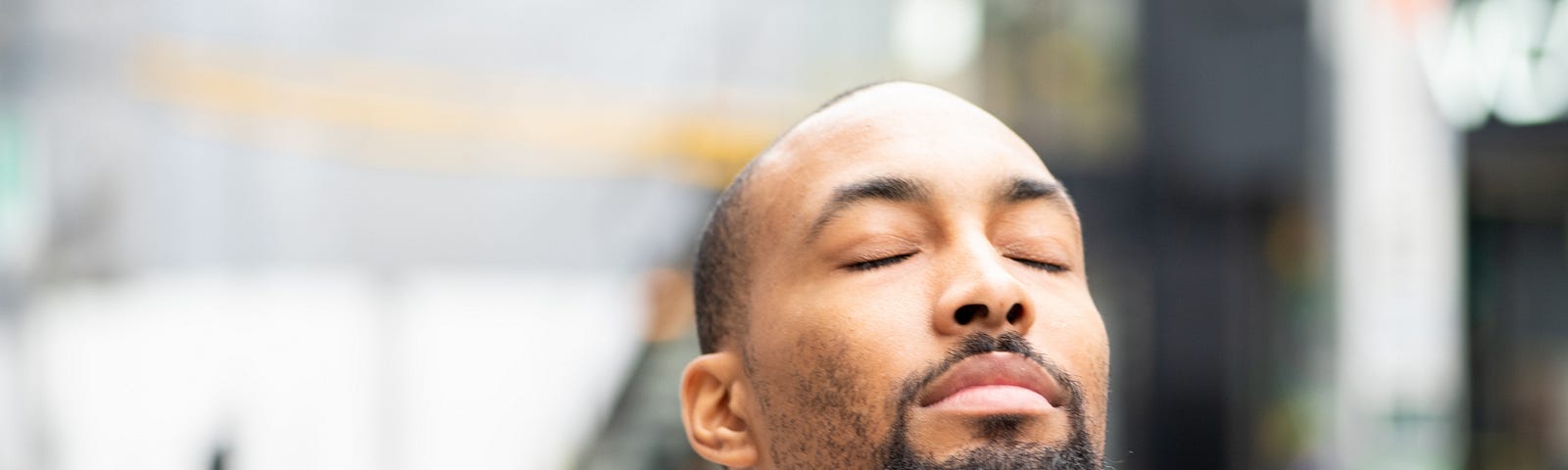 Young Black man closing his eyes with a peaceful expression.