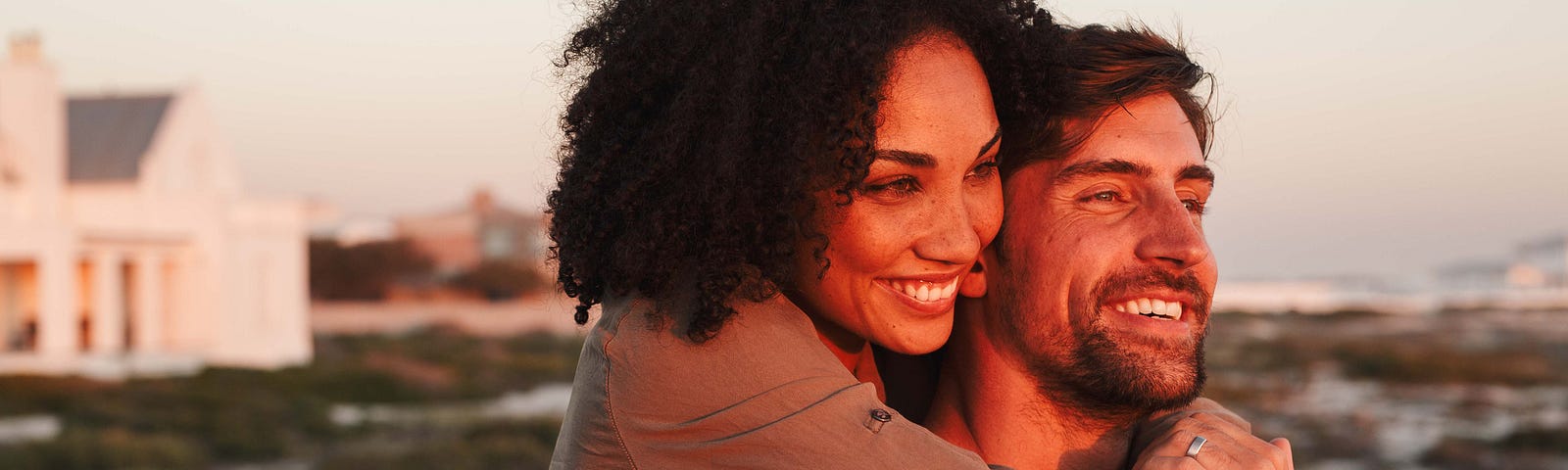 Multiracial couple embracing while watching a sunset.