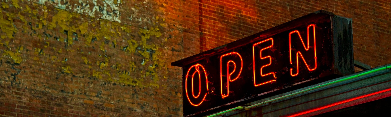 A photo of a neon OPEN sign on top of a business storefront.