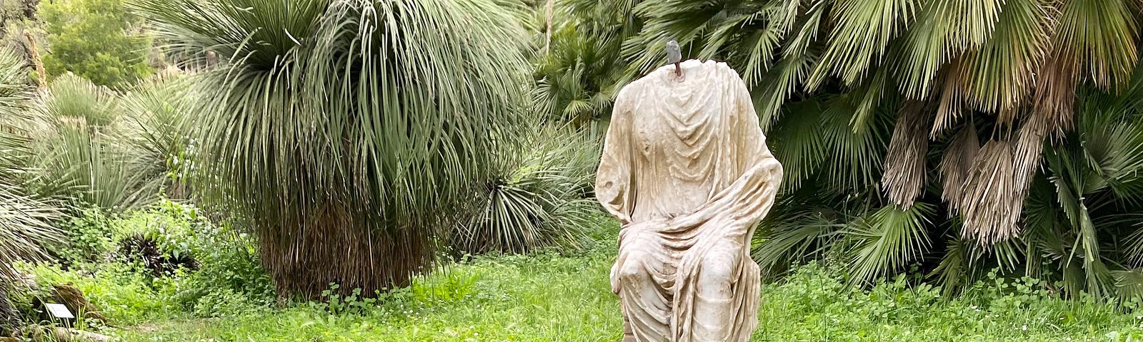 A headless statue sitting on the edge of a lily pond.