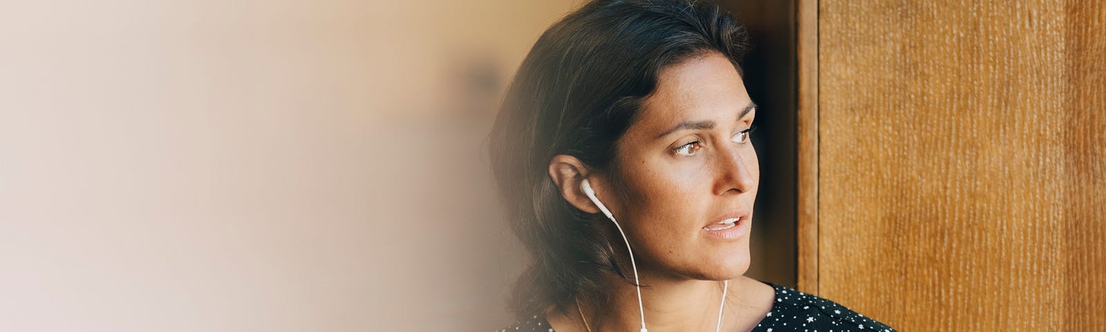 A businesswoman holding a coffee cup while talking on earphones in office