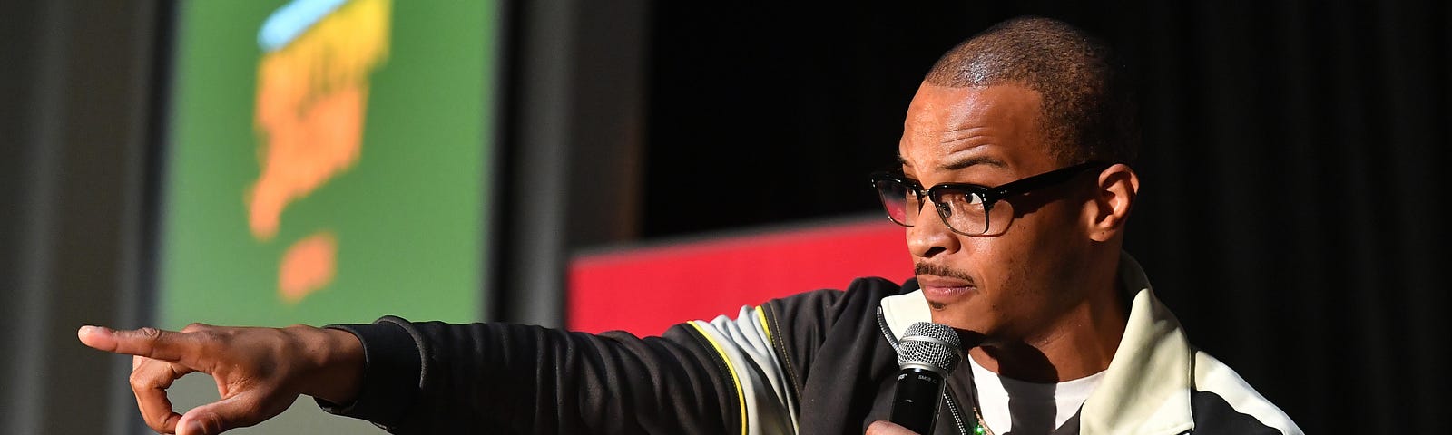 A photo of T.I. onstage pointing with his left arm into the crowd.