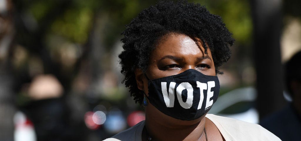 Stacey Abrams wearing a face mask that says “VOTE.”