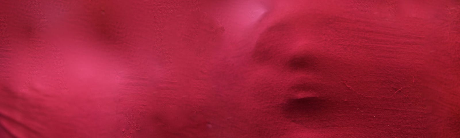 A screaming face coming through red fabric.