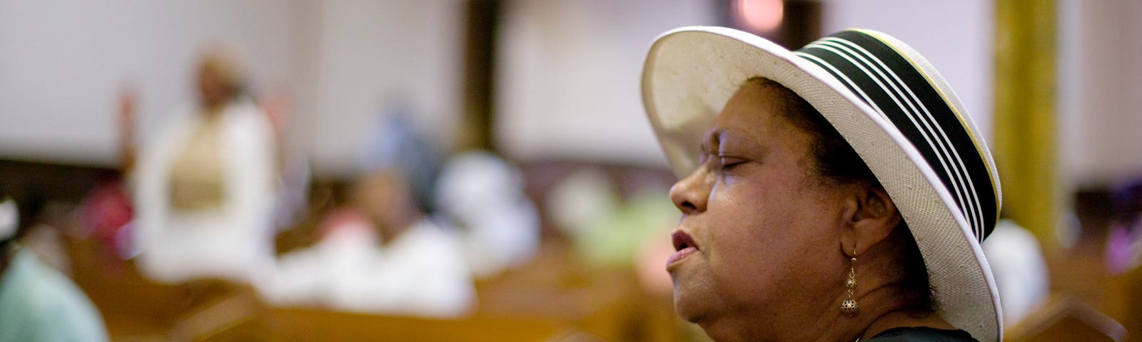 A photo of a black woman singing at church.