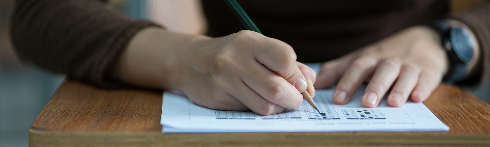 Student taking a multiple choice test while sitting at desk.