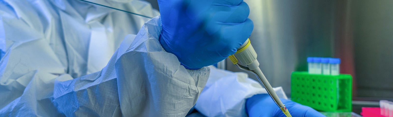 Photo of a researcher wearing gloves and safety gear pipetting into tubes.