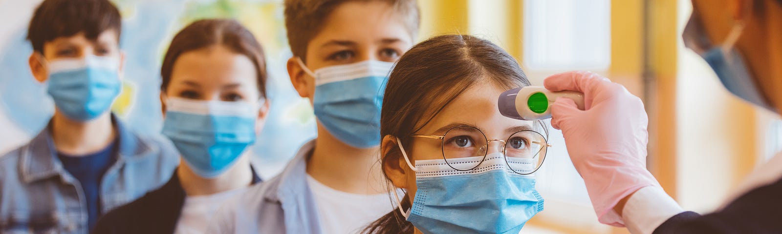 Students wearing face masks getting their temperature checked at school.