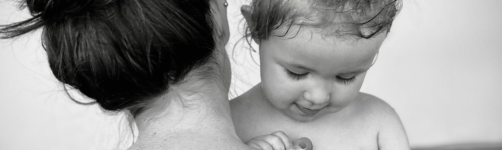 A black and white photo of a mother and her daughter embracing in a bathtub