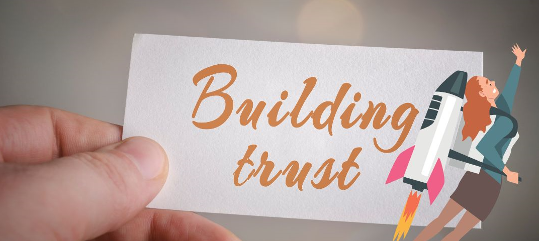 Hand holding a piece of paper with the words ‘Building Trust’ written on it, symbolizing the leadership skill of fostering trust within a team.