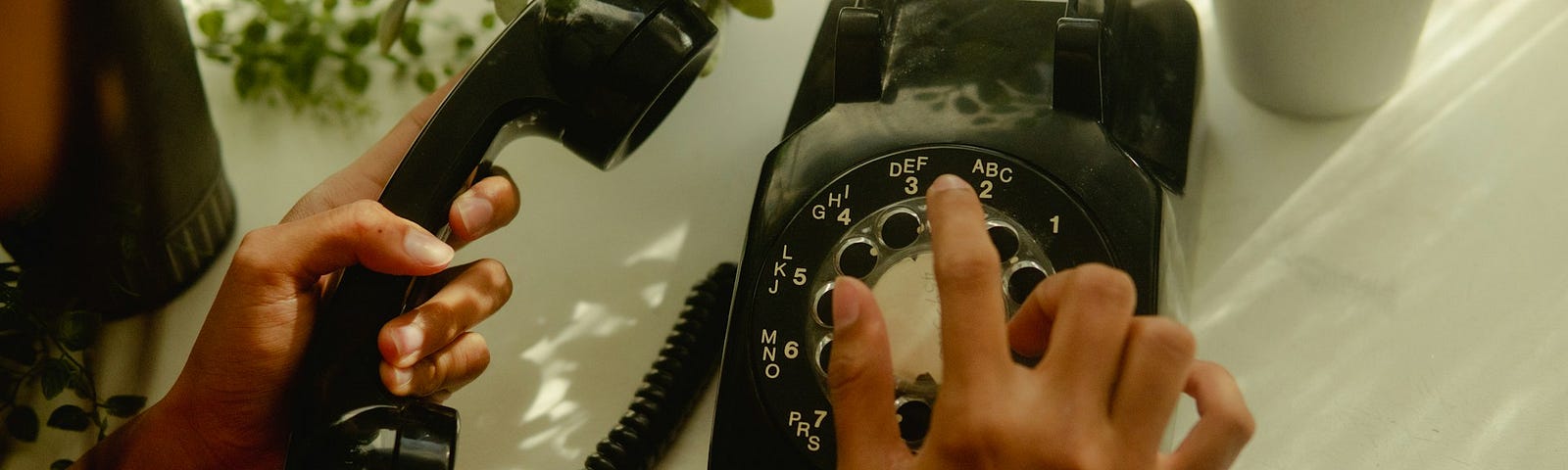 Overhead view of a woman holding a phone handset in her left hand while dialing with her right.