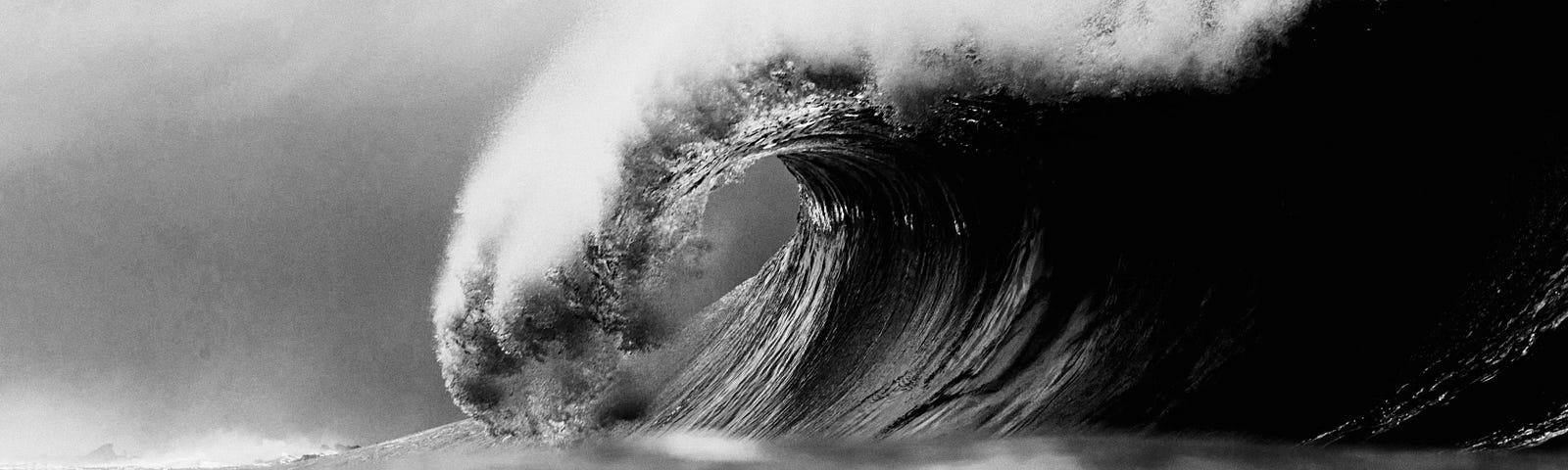 Black and white photo of a tsunami wave cresting.
