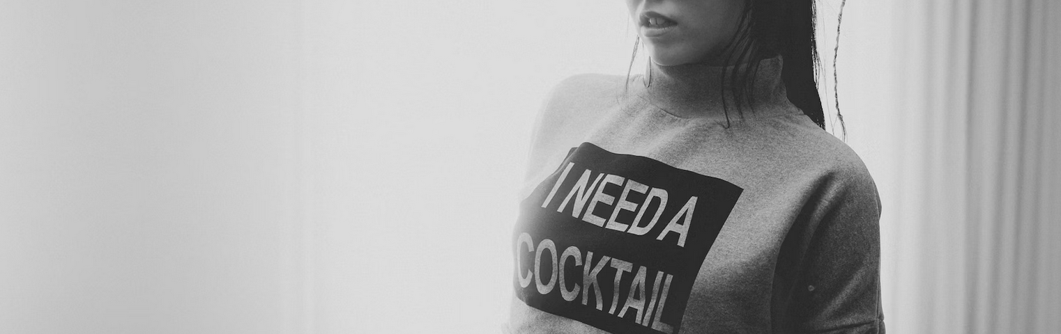 Woman wearing a long sleeve shirt with the words “I need a cocktail”