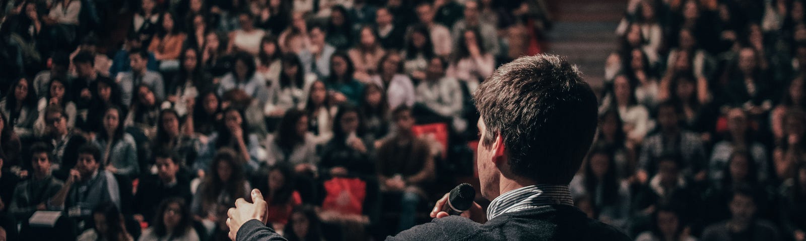 A man gives a lecture to an auditorium full of students.