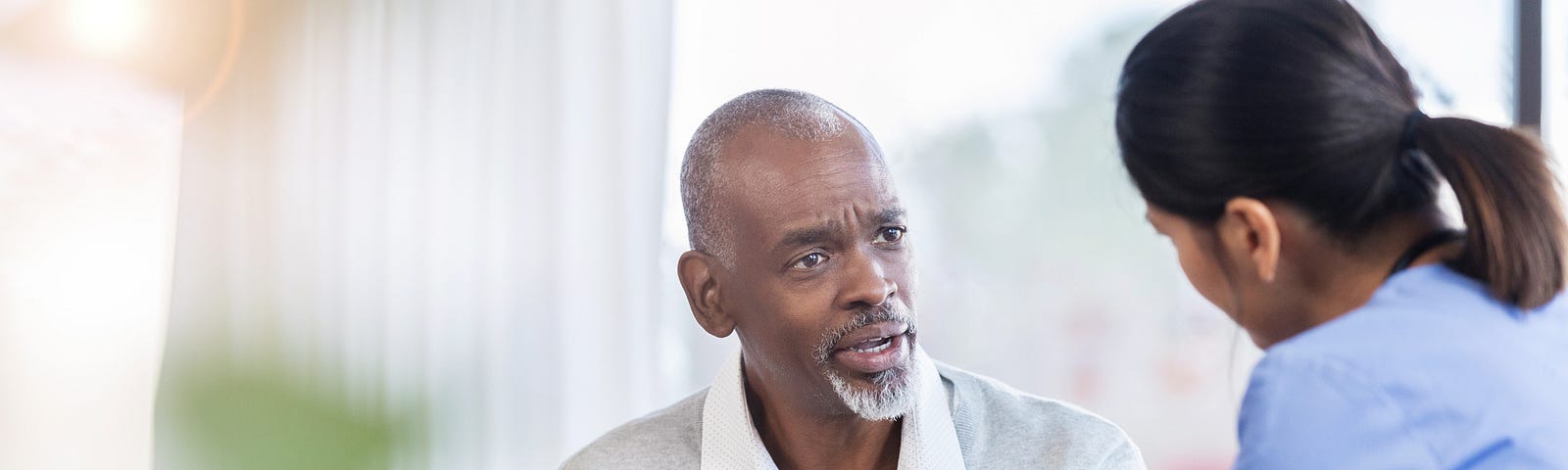 A man asks his doctor a question while pointing at his diagnosis on the tablet.