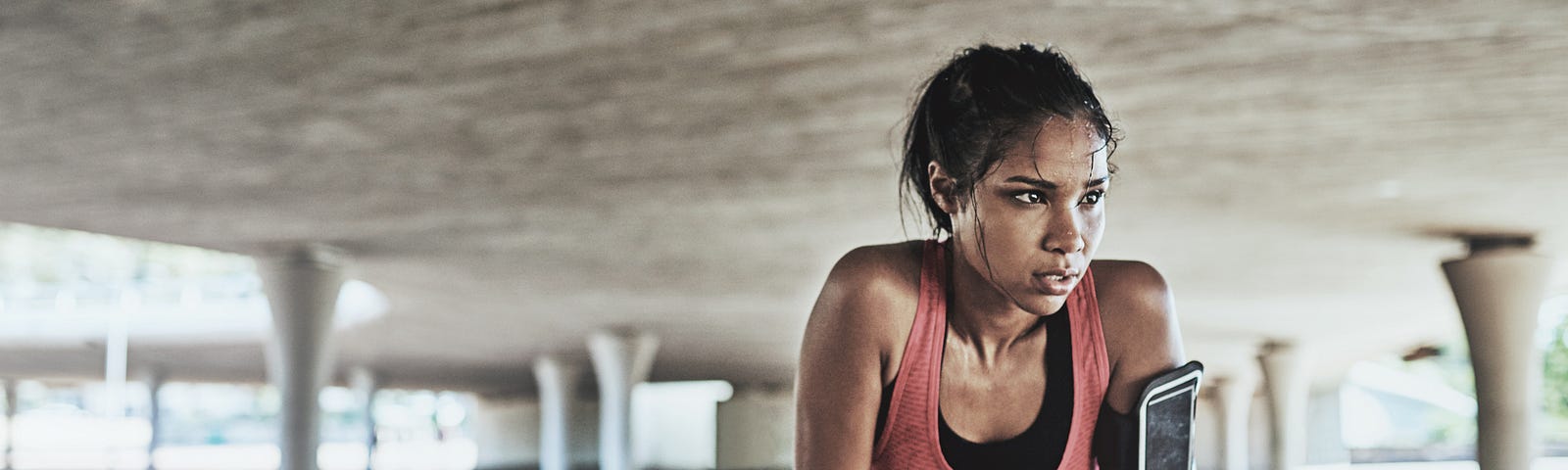 A sweaty young woman takes a break while exercising outdoors.