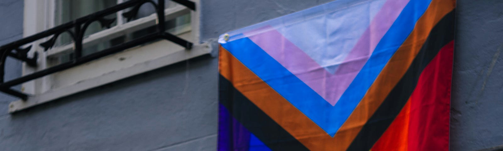 Progress Pride Flag hanging out of a building window