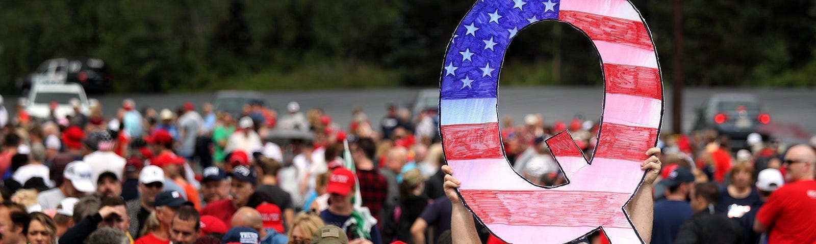 A man holds up a “Q” sign while waiting in line to see President Donald Trump at his rally on August 2, 2018 in Wilkes Barre, Pennsylvania.