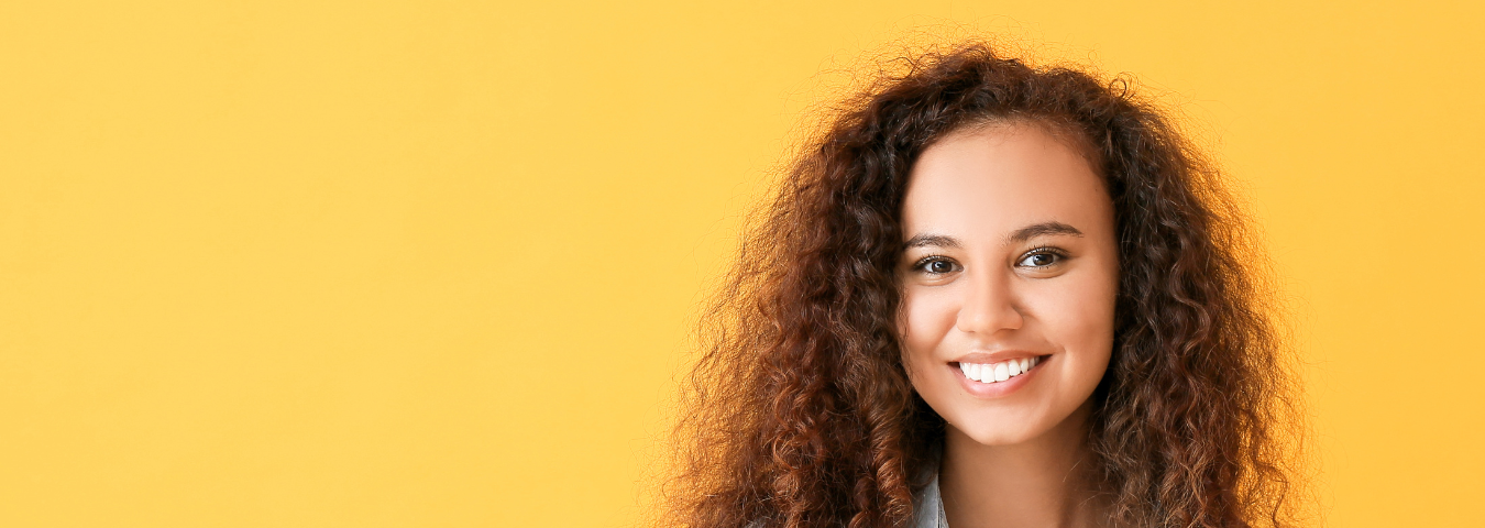 Young woman with tablet computer on yellow background.