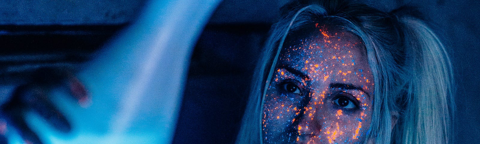 A woman covered in neon speckles holds up a beaker