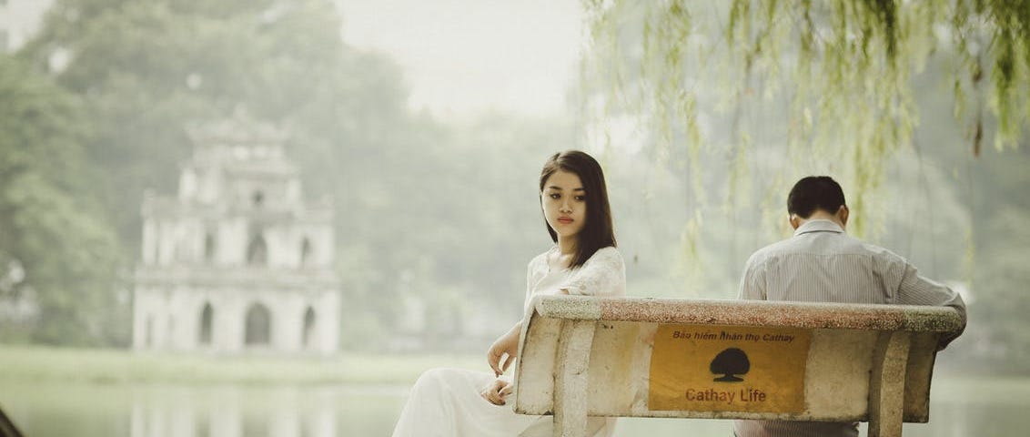 Two people sit on a bench in front of a lake, looking away from each other unhappily. #breakup #relationship #fight