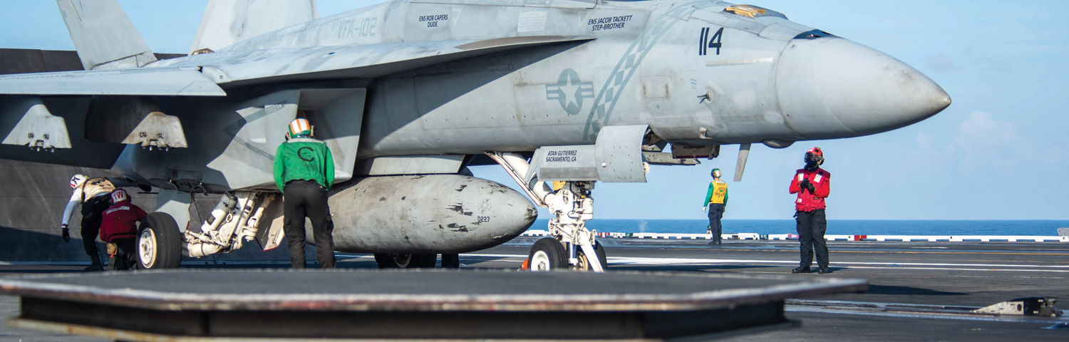 Photo of a fighter jet on an aircraft carrier.