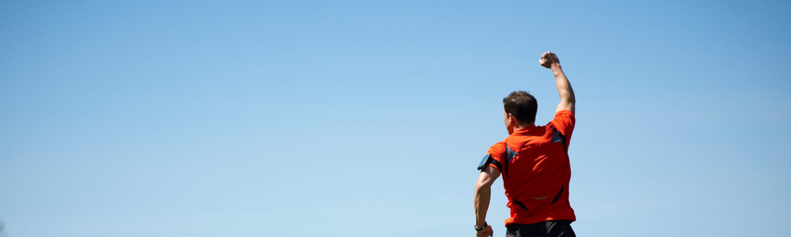 A male mountain runner is jumping up and punching the air.