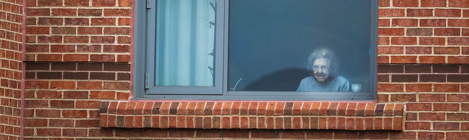 An older female resident at The Leonard Florence Center for Living looks outside her window.