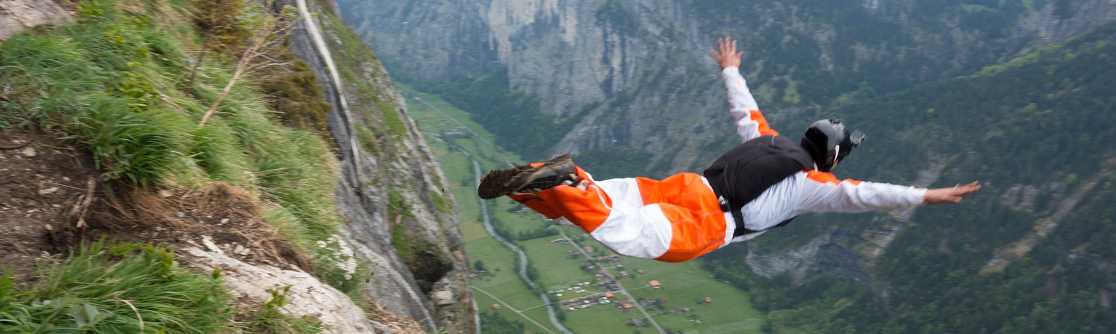 Base jumper diving  down into a valley.