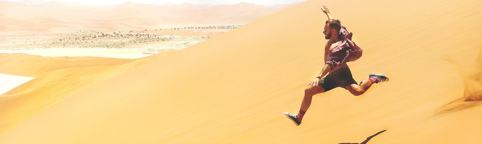 man running swiftly down a large sand dune