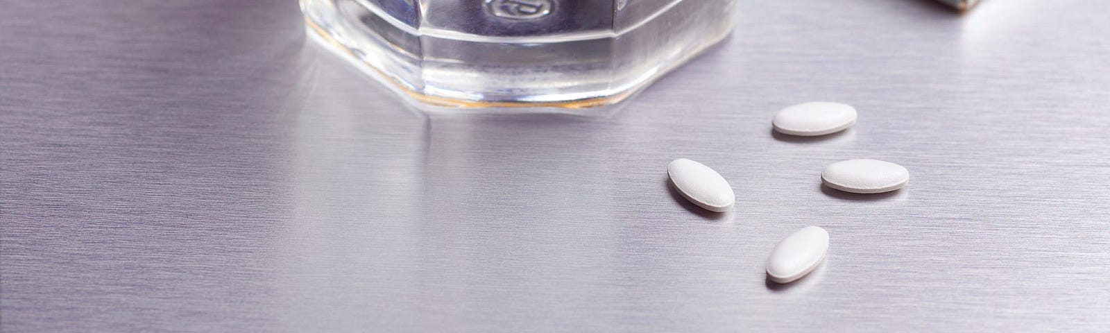 Glass of water with pills beside it