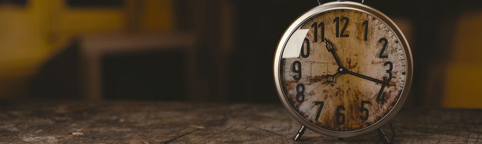 Old small clock sitting on wooden table