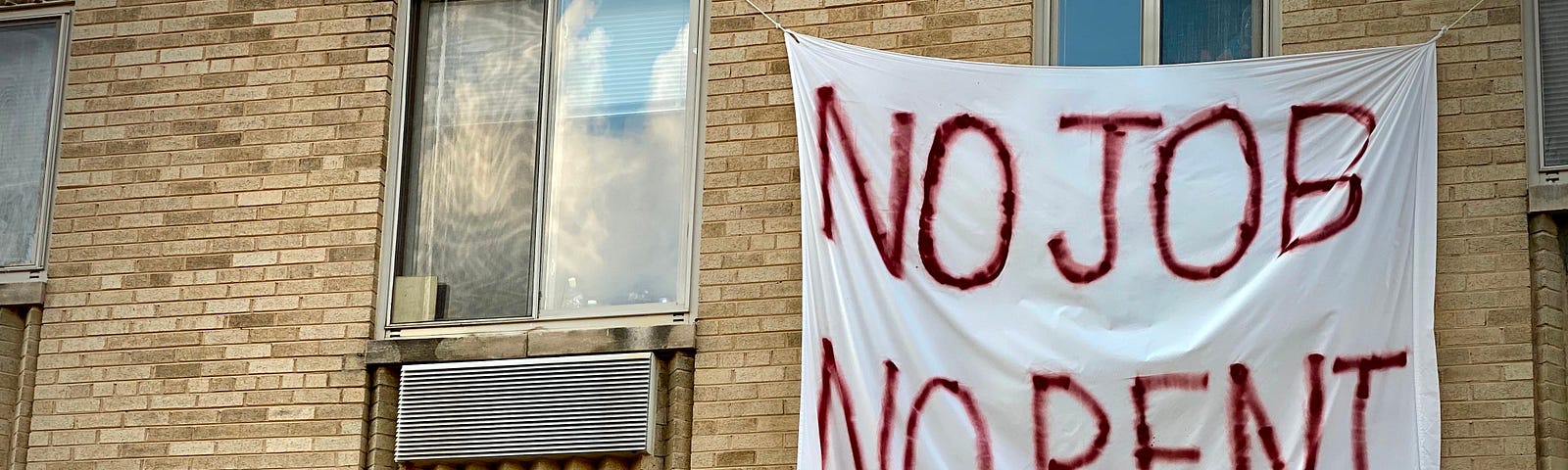 A banner against renter’s eviction reading “No Job No Rent” on the side of a rent-controlled building in Washington, DC.