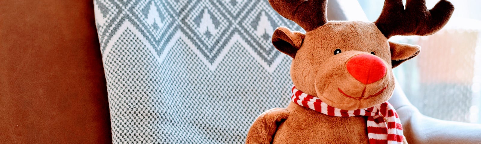 moose stuffie with a red and white striped scarf and a red nose.