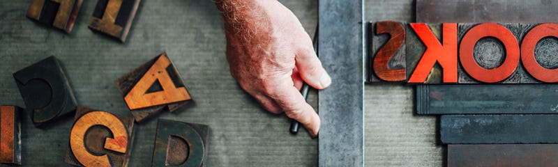 A hand lining up text on a letterpress machine