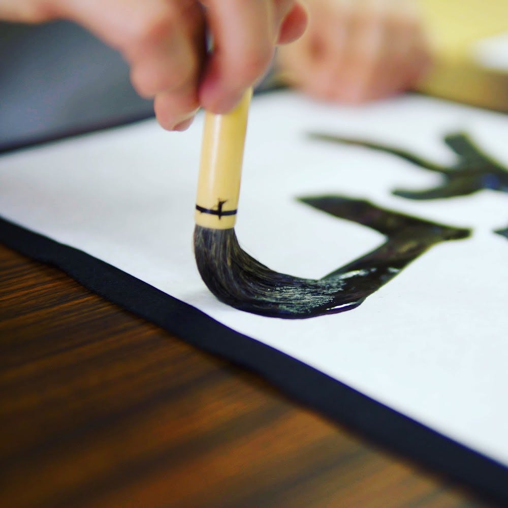 A brush full of black ink runs across a white piece of paper to form the Chinese character of Harmony at Zenpoji Temple in Tsuruoka City, Yamagata Prefecture.