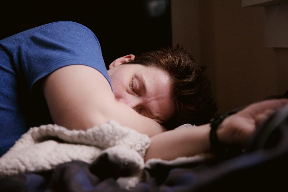 A photograph of a man wearing a blue shirt, lying down, seemingly tired and lethargic