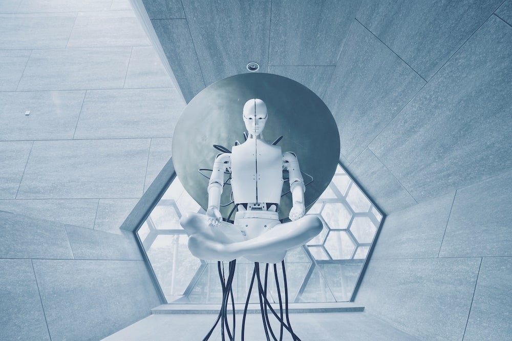 A white robot floats in mid-air in lotus yoga pose while wires are attached to it, keeping it grounded in a hexagonal-shaped gray room