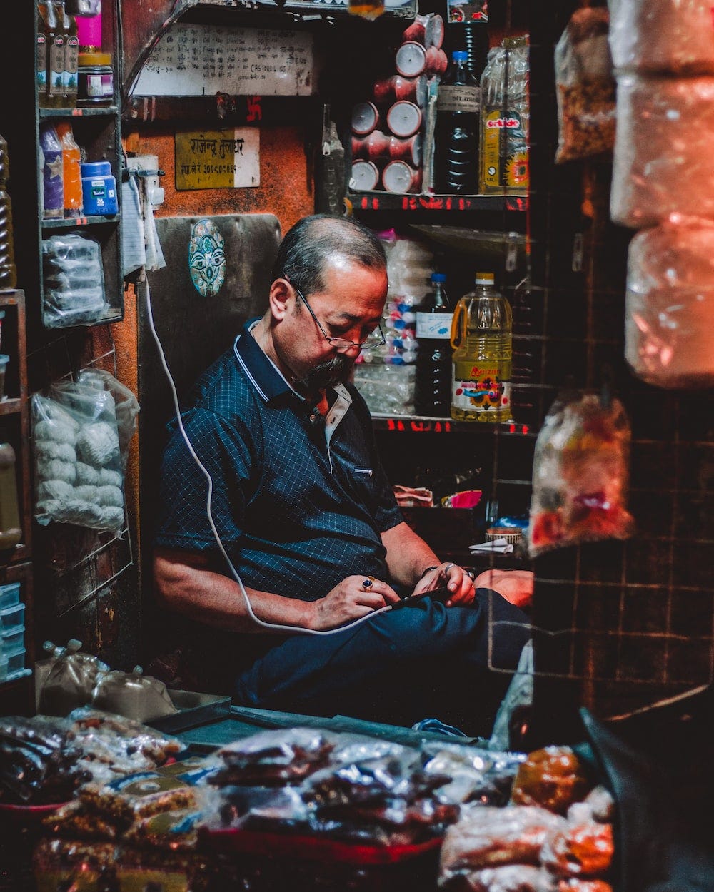 A shopkeeper browsing dumbly through his phone.