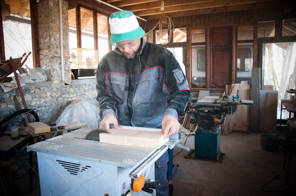 Crafting with precision in a studio, a man skillfully works with wood, either repairing or building.