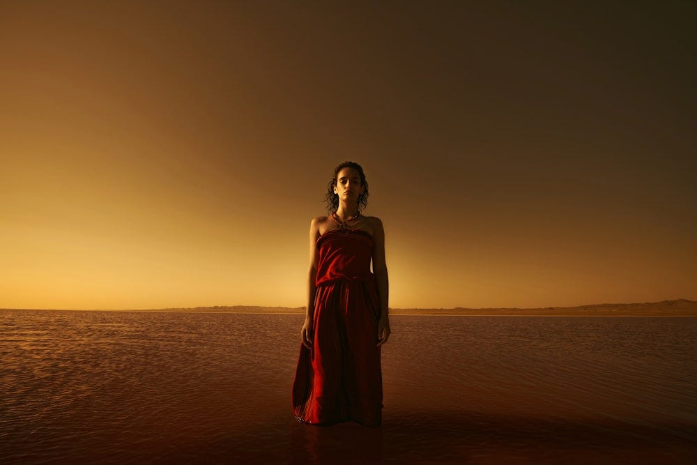 Young woman in a red gown in dark desert landscape