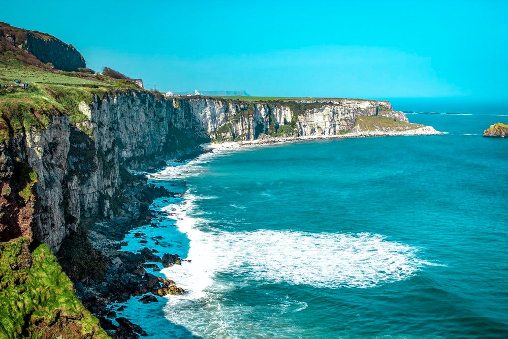 Picture of a cliff by the sea with Rope Bridge, Ireland in the background