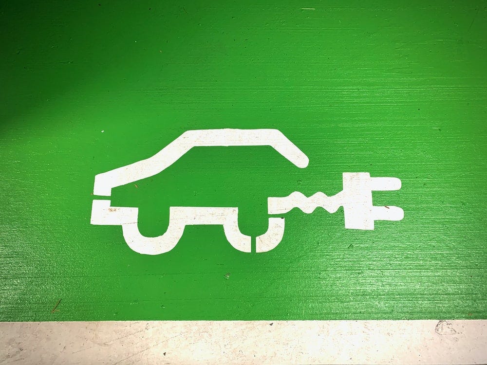 A simple sketch of the outline of a hybrid car, white against green background.