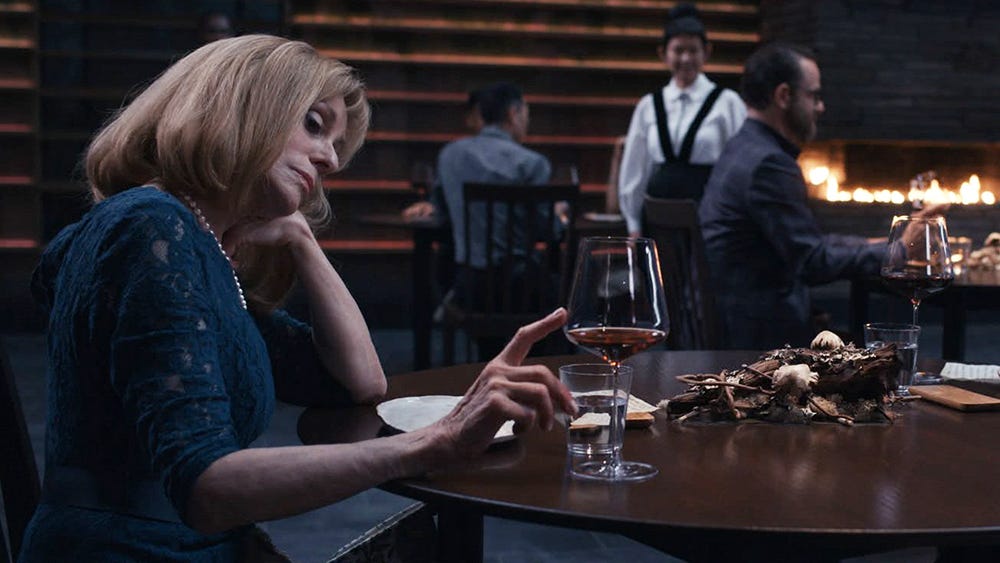 An image shows Judith Light as Anne Leibrandt sitting at the table with her head resting on one palm. The other hand touches the half-drunk wine glass.