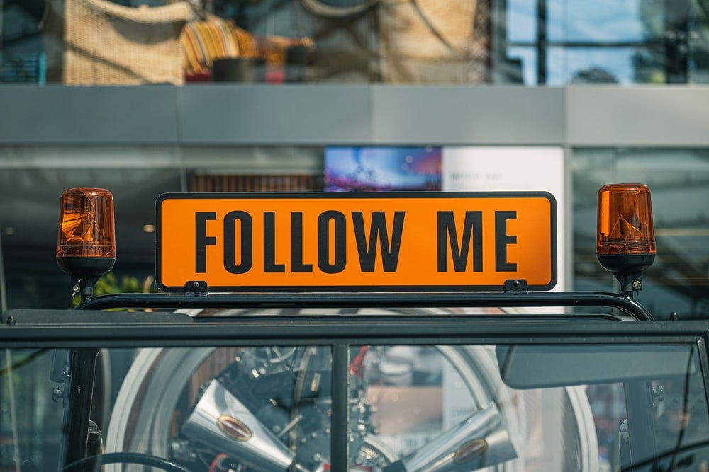 “Follow Me” lighted sign set between two flashing lights.